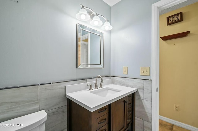 half bathroom with tile walls, a wainscoted wall, toilet, and vanity