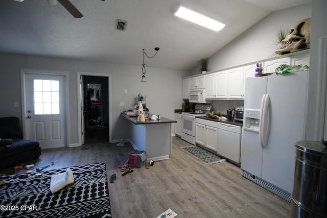 kitchen with dark countertops, visible vents, light wood-type flooring, vaulted ceiling, and white appliances