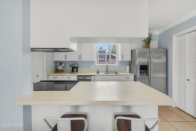 kitchen with a breakfast bar area, stainless steel appliances, light tile patterned floors, white cabinets, and a sink