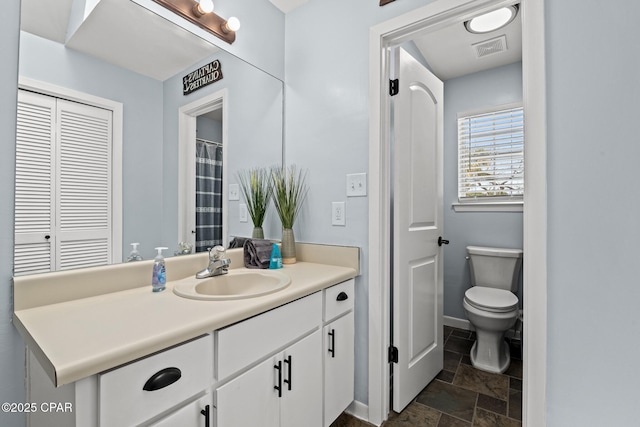 full bathroom with stone finish floor, toilet, vanity, baseboards, and visible vents