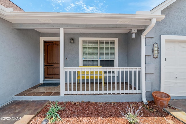 doorway to property with covered porch and stucco siding