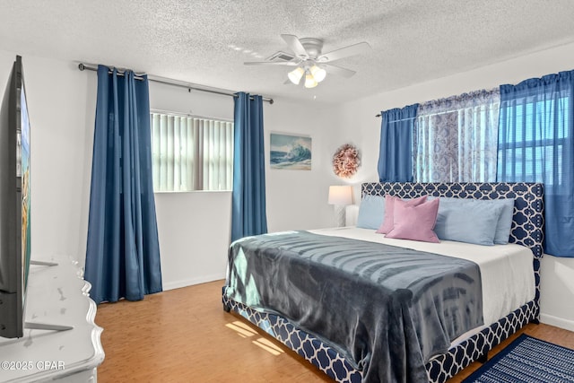 bedroom featuring baseboards, a textured ceiling, ceiling fan, and wood finished floors