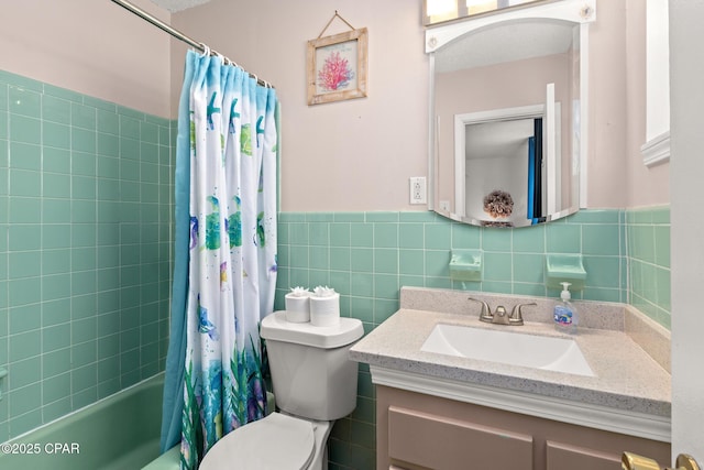 bathroom with shower / bath combo, vanity, toilet, a wainscoted wall, and tile walls