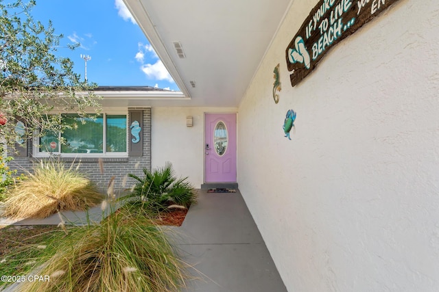 doorway to property featuring stucco siding