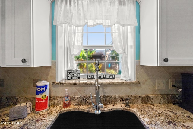 interior details featuring a sink, decorative backsplash, and white cabinets