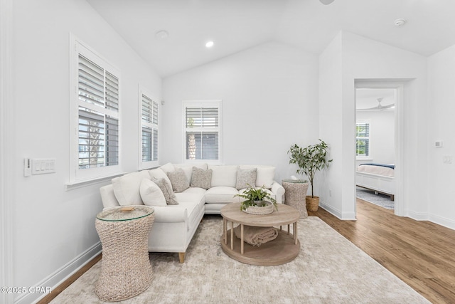 living room featuring baseboards, vaulted ceiling, plenty of natural light, and wood finished floors