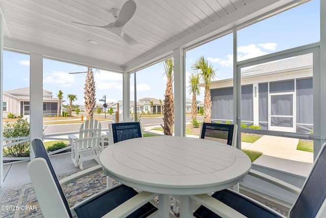 sunroom with a residential view, a ceiling fan, and outdoor dining area