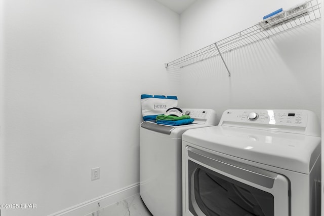 washroom with baseboards, laundry area, washing machine and dryer, and marble finish floor