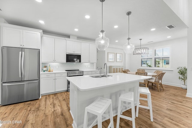 kitchen with white cabinetry, appliances with stainless steel finishes, a sink, and light wood-style flooring