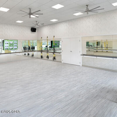 workout area with ceiling fan, a drop ceiling, a high ceiling, and wood finished floors