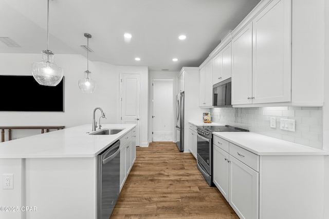 kitchen featuring visible vents, a sink, white cabinets, stainless steel appliances, and an island with sink