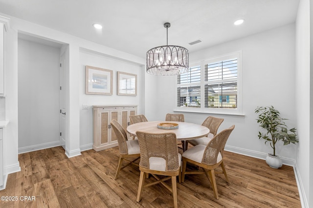 dining space with an inviting chandelier, light wood-style floors, baseboards, and visible vents