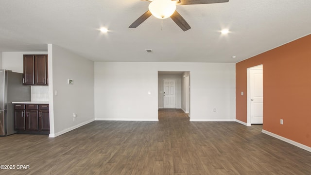 unfurnished living room featuring dark wood-style flooring, ceiling fan, visible vents, and baseboards
