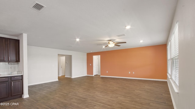 unfurnished living room featuring dark wood-style flooring, visible vents, and ceiling fan
