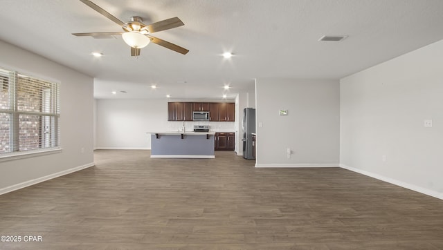 unfurnished living room with ceiling fan, visible vents, dark wood finished floors, and baseboards