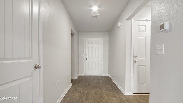 corridor featuring visible vents, wood finished floors, and baseboards