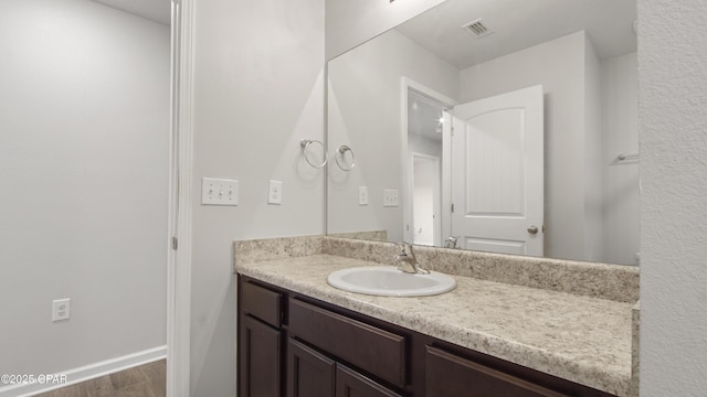 bathroom featuring vanity, visible vents, wood finished floors, and baseboards