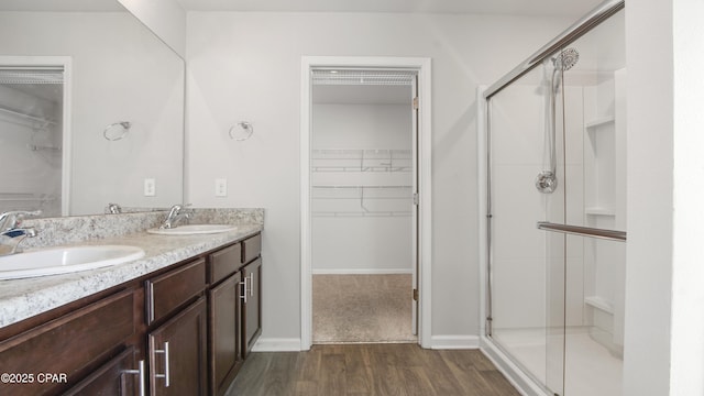 full bathroom featuring wood finished floors, a stall shower, and a sink