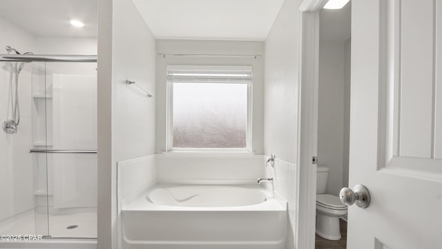 bathroom featuring a garden tub, toilet, and a shower stall