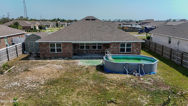 rear view of property with brick siding, a fenced backyard, a residential view, and a storage shed