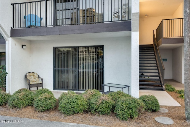 entrance to property featuring stucco siding and a balcony