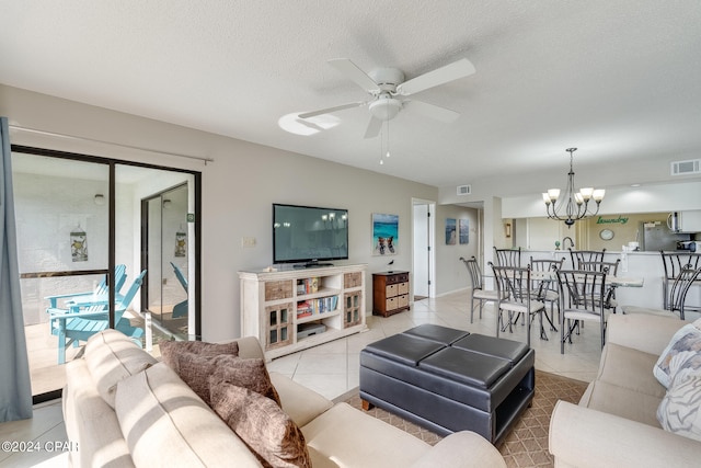 tiled living area featuring a textured ceiling, visible vents, and ceiling fan with notable chandelier