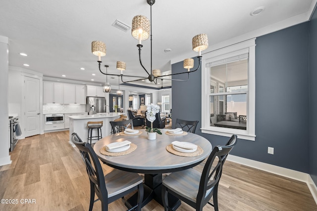 dining area with light wood finished floors, recessed lighting, an inviting chandelier, visible vents, and baseboards