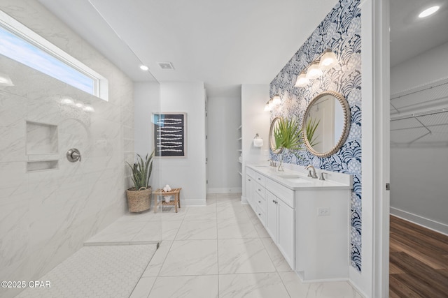 bathroom featuring double vanity, visible vents, baseboards, and a sink