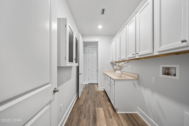washroom with baseboards, hookup for a washing machine, cabinet space, and dark wood-style flooring