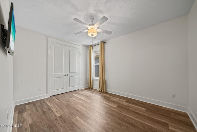 unfurnished bedroom with baseboards, wood finished floors, ceiling fan, and a textured ceiling