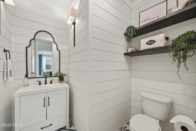 half bathroom with wooden walls, toilet, and vanity