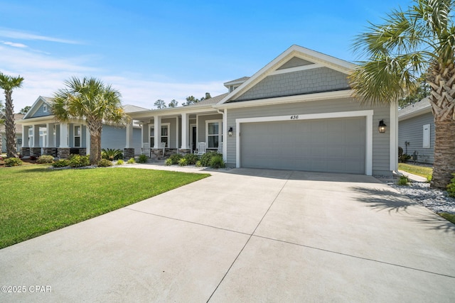view of front facade with a porch, a front yard, concrete driveway, and an attached garage