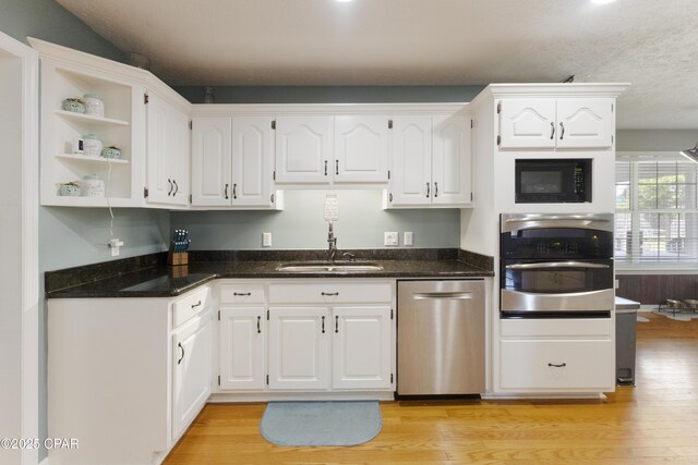 924 N College Blvd, Lynn Haven, FL 32444 - kitchen with dark stone counters, light wood finished floors, a sink, stainless steel appliances, and white cabinets
