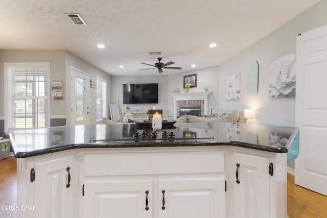 924 N College Blvd, Lynn Haven, FL 32444 - kitchen featuring a fireplace, ceiling fan, visible vents, light wood-style flooring, and a kitchen island