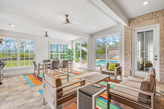 sunroom with beam ceiling, a wealth of natural light, stone finish flooring, and recessed lighting