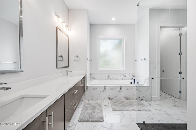 bathroom featuring a sink, a garden tub, and marble finish floor