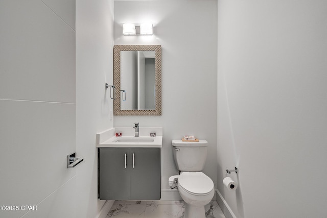 bathroom featuring toilet, marble finish floor, vanity, and baseboards