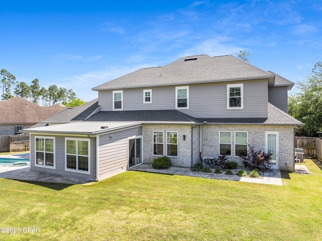 back of property with a fenced backyard, a yard, roof with shingles, central AC, and a patio area