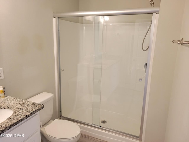 bathroom featuring vanity, a stall shower, and toilet