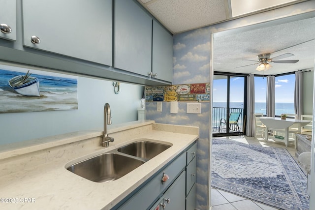 9850 S Thomas Dr Unit 810E, Panama City, FL 32408 - kitchen with a sink, a water view, gray cabinetry, ceiling fan, and light tile patterned floors