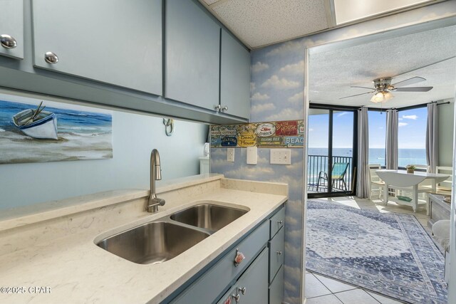 9850 S Thomas Dr Unit 810E, Panama City, FL 32408 - kitchen with a sink, a water view, a ceiling fan, light tile patterned flooring, and gray cabinets