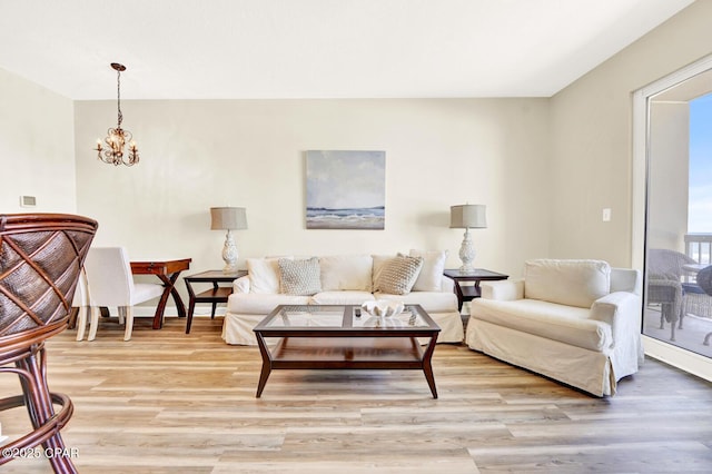 living room with light wood-type flooring, a chandelier, and baseboards