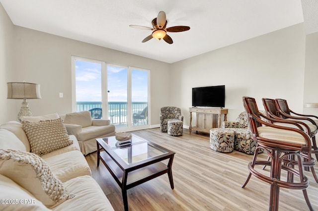 living area with light wood-style flooring, ceiling fan, and baseboards