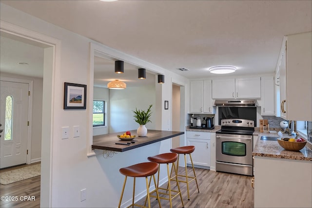 7851 Jenkins St, Sneads, FL 32460 - kitchen featuring under cabinet range hood, stainless steel electric range, white cabinets, and light wood-style floors