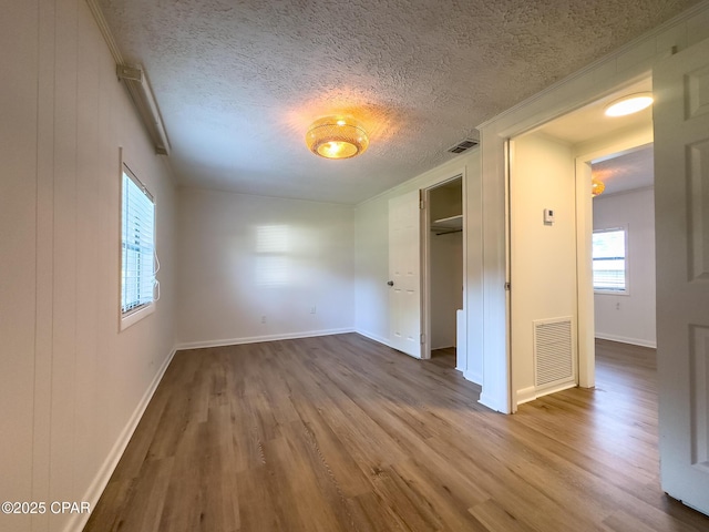 unfurnished bedroom featuring visible vents, multiple windows, and wood finished floors