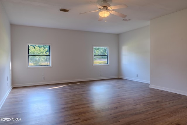 unfurnished room featuring baseboards, ceiling fan, dark wood finished floors, and visible vents