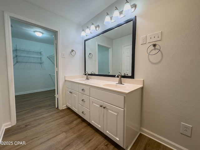 bathroom featuring a sink, baseboards, double vanity, and wood finished floors