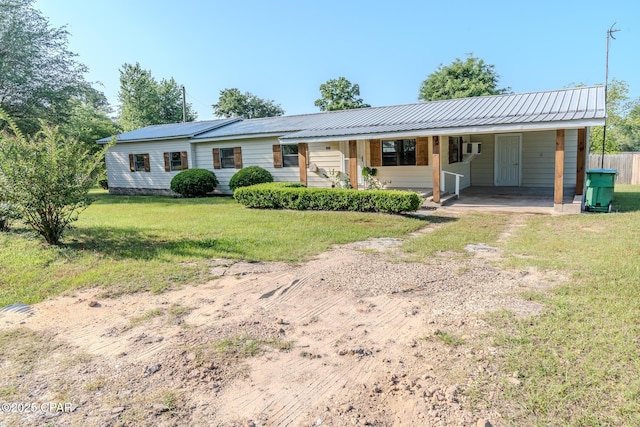 ranch-style house featuring a carport, metal roof, a front lawn, and dirt driveway