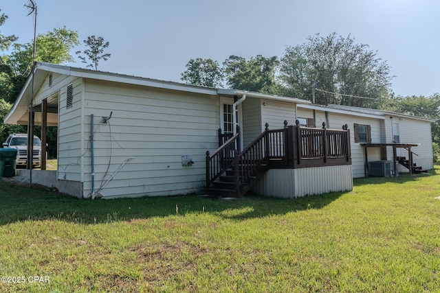 rear view of property featuring a lawn, central air condition unit, and stairs