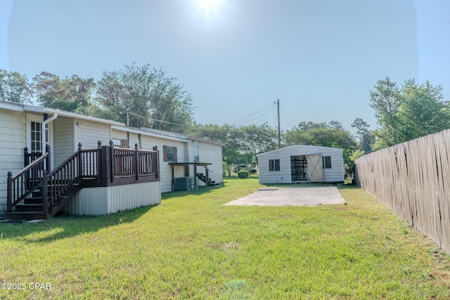 view of yard with fence, a patio, central air condition unit, an outbuilding, and stairway